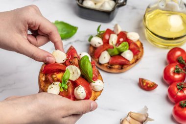 Kadın elleri mutfakta Caprese Bruschetta 'yı hazırlıyor. Lezzetli kahvaltı ya da atıştırmalık, temiz yemek, diyet, vejetaryen yemek konsepti. en üstteki görünüm.