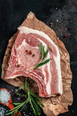 Esmer arka planda baharatlı ve otlu çiğ et. Çiğ domuz eti, pirzola. Restoran menüsü, diyet, yemek kitabı tarifi. Üst görünüm.