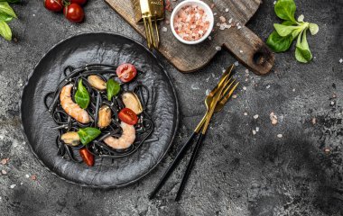 Karides ve midyeli siyah spagetti. Karanlık arka planda. Siyah spagetti. afiş, menü, metin için tarif yeri, üst görünüm.