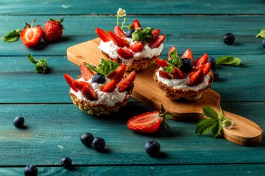 Şefin ellerinde kremalı, çilekli ve yaban mersinli meyveli turtalar. Metin için pankart menüsü tarifi yeri.