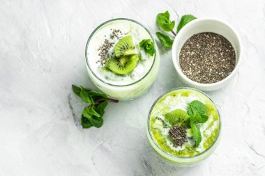 Bardakta Chia pudingi. Sağlıklı kahvaltı. Hafif arka planda kivili chia pudingi. Uzun afiş biçimi. en üstteki görünüm.