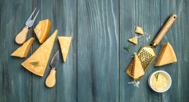 Parmesan peyniri dilimlenmiş ve rendelenmiş. Tahta arka planda bıçaklı bir parmesan peyniri seti. Uzun afiş biçimi. en üstteki görünüm.