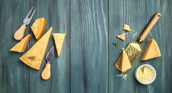 Parmesan peyniri dilimlenmiş ve rendelenmiş. Tahta arka planda bıçaklı bir parmesan peyniri seti. Uzun afiş biçimi. en üstteki görünüm.