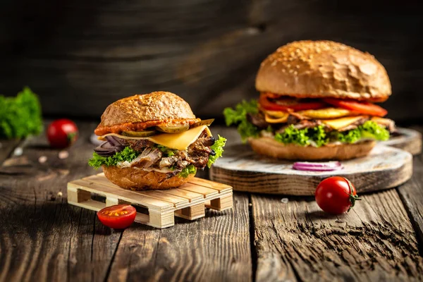 Ahşap arka planda servis edilen roka ve küflü peynirli etli iki Lezzetli burger. Fast food ve abur cubur kavramı.
