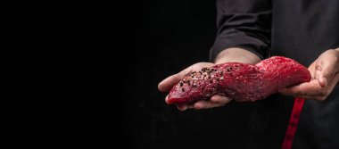 Erkek elleri koyu bir arka planda sığır eti tutuyor, biftekli ve baharatlı fileto parçası pişirmeye hazır, uzun afiş formatında.,