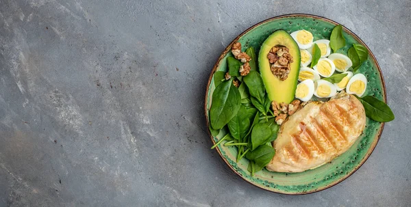 Low carb high fat breakfast. Ketogenic diet. avocado, grilled chicken fillet, quail egg, spinach, walnut, Long banner format. top view.