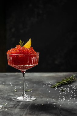 Bir kaşıkta kırmızı havyar. Siyah arka planda kase havyar. Yakın çekim somon havyar. Şarküteri. Gurme yemek. Havyar dokusu. Deniz ürünleri.