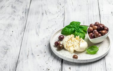 Beyaz tabakta fesleğenli ve zeytinyağlı kremalı İtalyan Burrata peyniri. İtalyan Akdeniz mutfağı. Uzun afiş biçimi. en üstteki görünüm,