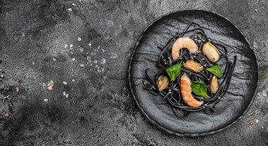 Karidesli ve midyeli siyah spagetti tabağı. Karanlık arka planda. Siyah spagetti. afiş, menü, metin için tarif yeri, üst görünüm,