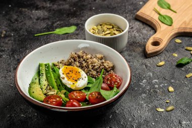 İçinde avokado, yumurta, domates, ıspanak ve ay çekirdeği olan kinoa budha kasesi. Ev yapımı yemek. Sağlıklı, temiz yemek. Vegan ya da glütensiz diyet, metin yeri, üst görünüm,