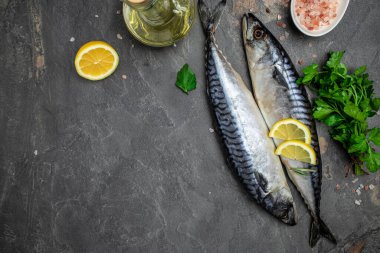 Raw Mackerel fish with salt, lemon and spices on dark background. Fresh seafood. Culinary, cooking fish concept. banner, menu, recipe place for text, top view.
