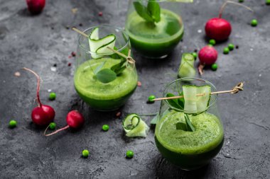 Beton arka planda bir bardakta salatalık yeşili smoothie tazeliyorum. Detox smoothie, taze bezelye, salatalık, turp, ıspanak ve limon..