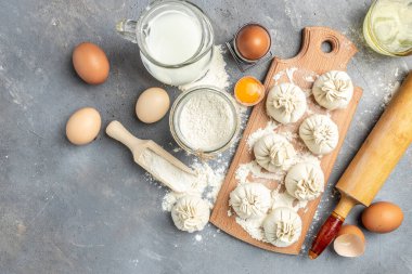 Etle çiğ Khinkali, tahtadan bir tahta üzerinde un, yarı bitmiş ürünler khinkali pişiriyor. Gürcistan hamur tatlısı.