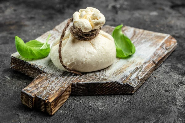 Puglia 'dan taze fesleğen yapraklı taze İtalyan peyniri, beyaz burrata topları ya da mozzarella peynirinden yapılmış burratina peyniri ve ahşap bir tahtanın üzerine doldurulmuş krema..