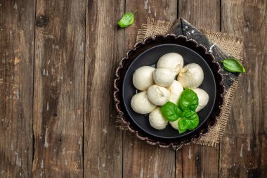 Geleneksel mozzarella peyniri. Koyu ahşap arka planda taze fesleğen yaprakları. afiş, menü, metin için tarif yeri, üst görünüm.