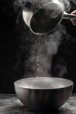 Siyah arka planda pişirme kabı, sıcak yemek. Bir kase sıcak buhar dumanı, mutfak, yemek pişirme, konsept,