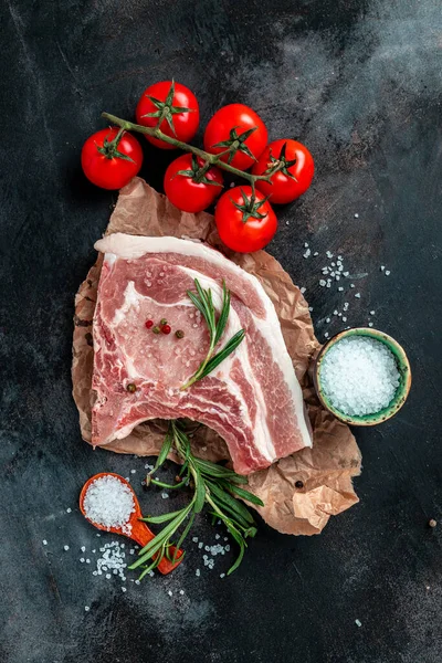 Kaburgalı domuz eti. Tavada çiğ domuz pirzolası. Tenderloin. Entrecote. Organik yiyecekler. dikey görüntü. Üst Manzara. metin için yer.