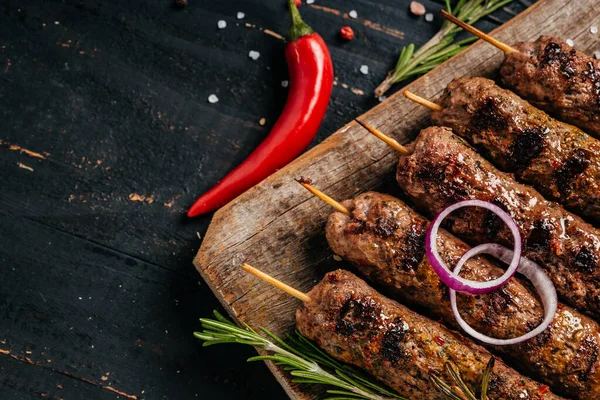 Sığır eti kıyma üzerinden bir çubuk üzerinde şiş kebap. Lula kebap, geleneksel Kafkas çanak. Ketçap ile bir kesme tahtası üzerinde betonun siyah arka plan üzerine alan yukarıdaki baharat ve domates kopyalama