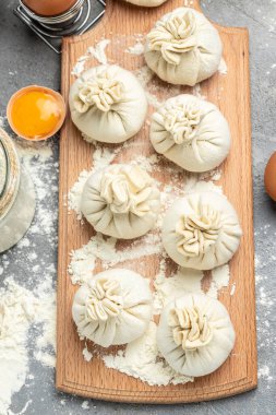 Çiğ khinkali ile tahta kesmek et, yarı bitmiş ürünler hamur köftesi. Khinkali pişirmek. Ulusal Gürcü mutfağı. dikey görüntü. en üstteki görünüm.