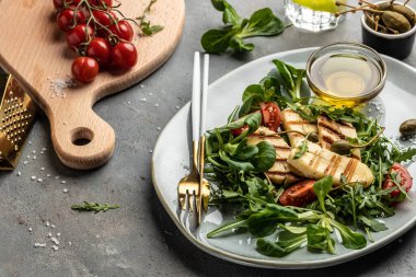 Izgara halloumi peynirli taze salata, domates, kapari, marul ve roka. Ketojenik paleo diyeti. Lezzetli kahvaltı ya da atıştırmalık, temiz yemek, diyet, vejetaryen yemek konsepti. en üstteki görünüm.