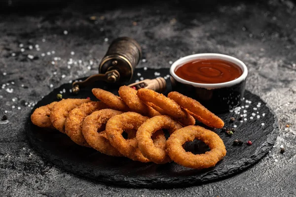 Fast food yemek soğan halkaları karanlık masada. Amerikan gıda konsepti. pankart, menü, tarif, metin için yer.