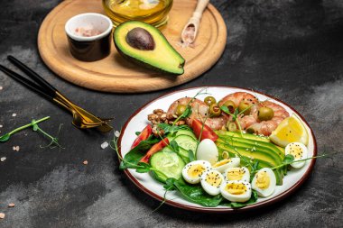 Ketojenik kahvaltı. Düşük karbonhidratlı karides, karides, bıldırcın yumurtası, taze salata, domates, salatalık ve avokado. Keto diyeti. Üst görünüm.