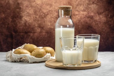 Bardakta patates sütü ve çiğ patates. Alternatif bitkisel süt. Süper yiyecek konsepti. Sağlıklı, temiz yemek. Vejetaryen ya da glütensiz diyet. en üstteki görünüm,