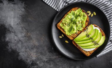 Kahvaltı veya çavdar ekmeği, avokado, roka, kabak ve susam, tuz ve biber dilimlenmiş ile öğle yemeği için sağlıklı avokado kızartır. Vejetaryen sandviç. Bitki temelli diyet. Tüm gıda kavramı.