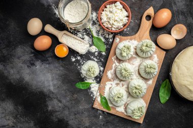Peynirli ve ıspanaklı Gürcü hamur tatlısı. Çiğ, yarı bitmiş meyveli börekler. afiş, menü, metin için tarif yeri, üst görünüm.