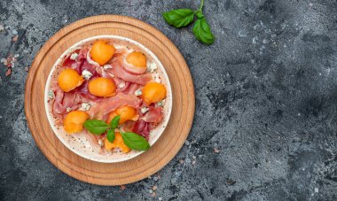 Taze kavunlu salata, jambonlu ve fesleğenli. Antipasti, geleneksel İspanyolca ve İtalyan aperatifleri. Uzun afiş biçimi. en üstteki görünüm.