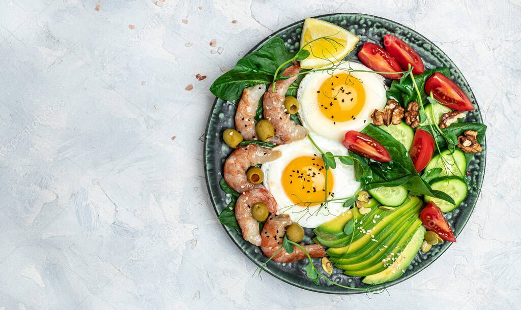 Ketogenic diet breakfast shrimps, prawns, soft fried egg, fresh salad, tomatoes, cucumbers and avocado on a light background. Keto, paleo lunch. Top view.