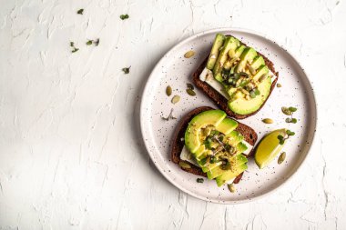 Sağlıklı avokado tostları, çavdar ekmeği dilimlenmiş avokado, peynir, balkabağı, fındık ve susamlı kahvaltı ya da öğle yemeği. Vejetaryen yemeği. Vejetaryen menüsü. en üstteki görünüm,