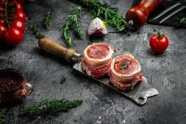 Çiğ mermer et, biftek fileminyonu. Eski kasap, aşçı ve yemek pişirme konseptinde servis edilen domuz pastırmasına sarılı madalyon biftekleri. Üst Manzara. metin için yer,