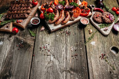 Barbekü menüsü. Tahta tahtada sebzeli leziz bbq aperatifleri ızgara et çeşitleri. afiş, menü, metin için tarif yeri, üst görünüm.