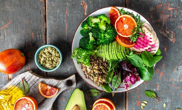 Healthy vegetarian dish with vegetables, avocado, blood orange, broccoli, watermelon radish, spinach quinoa, pumpkin seeds. Buddha bowl. Balanced food. Delicious detox diet. Top view.