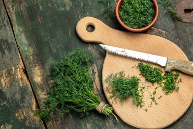 Kesme tahtasında doğranmış taze dereotu ve ahşap bir masada organik, sağlıklı, doğal ürünleri dondurmak için bir sürü dereotu hazırlığı. Üst görünüm,