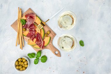 Akdeniz salatası jambon, mozzarella ve yeşil fesleğen yaprakları ve kavun kavunu beyaz masada, geleneksel İspanyol ve İtalyan aperatifi toptan Grissini ile servis edilir..