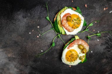 Tam ekmekli iki tost, yumurta, ıspanak, avokado, koyu arka planda karides, ketogenik kahvaltı. Süper yiyecek konsepti. Sağlıklı, temiz yemek. Üst görünüm.