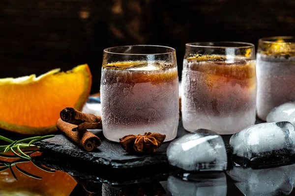 alcoholic drink and orange in ice glasses. Alcoholic booze cocktail. german digestif made with 56 herbs and spices.