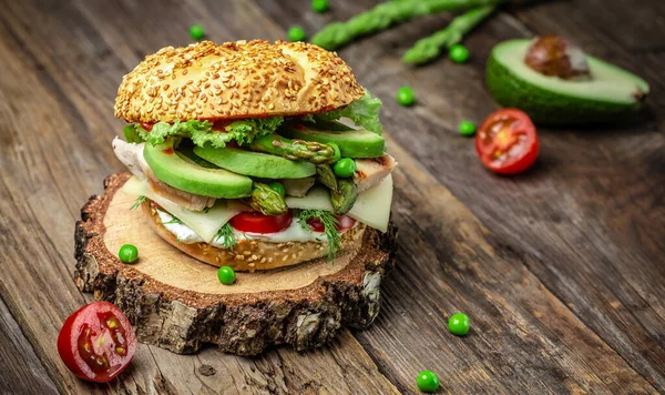 Delicious burgers with chicken fillet, asparagus, avocado, tomatoes, peas, cheese and tartar sauce. fast food and junk food concept.