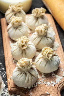 Etle çiğ Khinkali, tahtadan bir tahta üzerinde un, yarı bitmiş ürünler khinkali pişiriyor. Gürcistan hamur tatlısı.