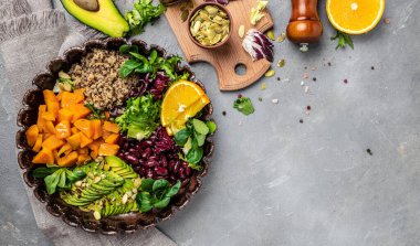 Gri arka planda kinoa salatası yapmak için gerekli malzemeler. Kasede sebze salatası, avokado, tatlı patates, fasulye, otlar. Temiz sağlıklı detoks yeme. Vejetaryen yemeği. Sağlıklı salata yapıyorum. en üstteki görünüm.