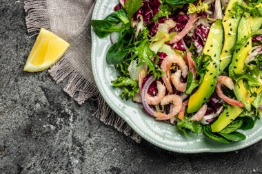 Taze avokado salatası, karides, marul yeşili karışım ve zeytinyağı, limon sosu. Sağlıklı yemek, lezzetli kahvaltı ya da atıştırmalık, temiz yemek, diyet, vejetaryen yemek konsepti. en üstteki görünüm.