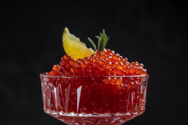 Bir kaşıkta kırmızı havyar. Siyah arka planda kase havyar. Yakın çekim somon havyar. Şarküteri. Gurme yemek. Havyar dokusu. Deniz ürünleri.