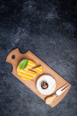 Camembert peyniri, Brie peyniri, Gorgonzola peyniri fesleğen yapraklı ve koyu arkaplanda vişne domatesli. dikey görüntü. Üst Manzara. metin için yer.