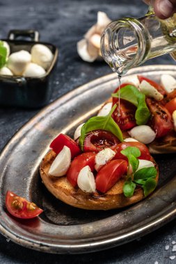 Mozzarella, kiraz domatesli ve taze fesleğenli Caprese tostları. Geleneksel İtalyan aperatifi veya aperatifi, antipasto. dikey görüntü. Üst Manzara. metin için yer,