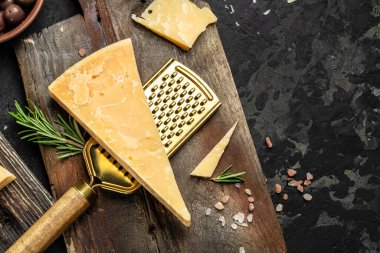Parmesan peyniri dilimlenmiş ve rendelenmiş. Tahta arka planda bıçaklı bir parmesan peyniri seti. Uzun afiş biçimi. en üstteki görünüm.