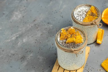 Narenciye ile süslenmiş camda laktozsuz yoğurt ile Chia Seed. Gri arka planda chia tohumlu yoğurt. sağlıklı süper yiyecekler. Sağlıklı yiyecekler. metin için yer.