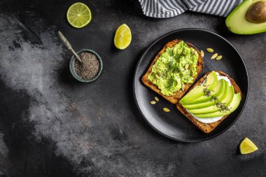 Kahvaltı veya çavdar ekmeği, avokado, roka, kabak ve susam, tuz ve biber dilimlenmiş ile öğle yemeği için sağlıklı avokado kızartır. Vejetaryen yiyecekler. Bitki temelli diyet. Temiz yemek. Üstten görünüm. Kopya alanı