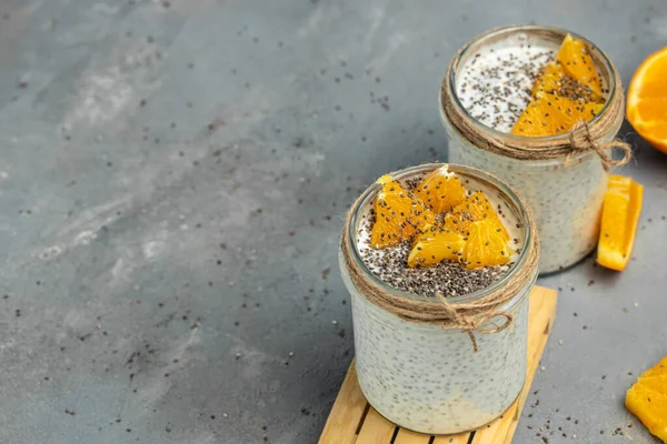 Chia Seed with lactose-free yogurt in glass decorated with citrus fruit. Yogurt with chia seeds on gray background. healthy superfood. Healthy food. place for text.